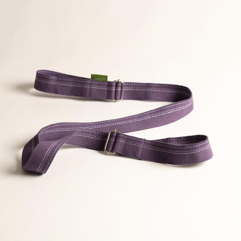 May include: Purple yoga strap with two metal buckles and a green label that says "Yogi"