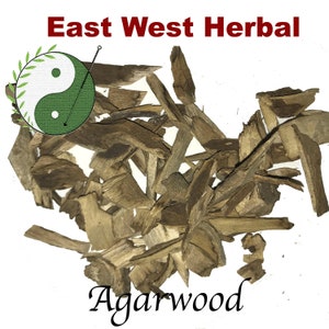 May include: A pile of brown wood chips, labeled "Agarwood" and "East West Herbal". The label also features a green and white yin yang symbol.