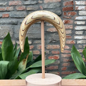 Könnte beinhalten: Eine halbmondförmige Skulptur aus Holz mit natürlicher Holzmaserung und roten Streifen. Die Skulptur ist auf einem Holzsockel montiert.