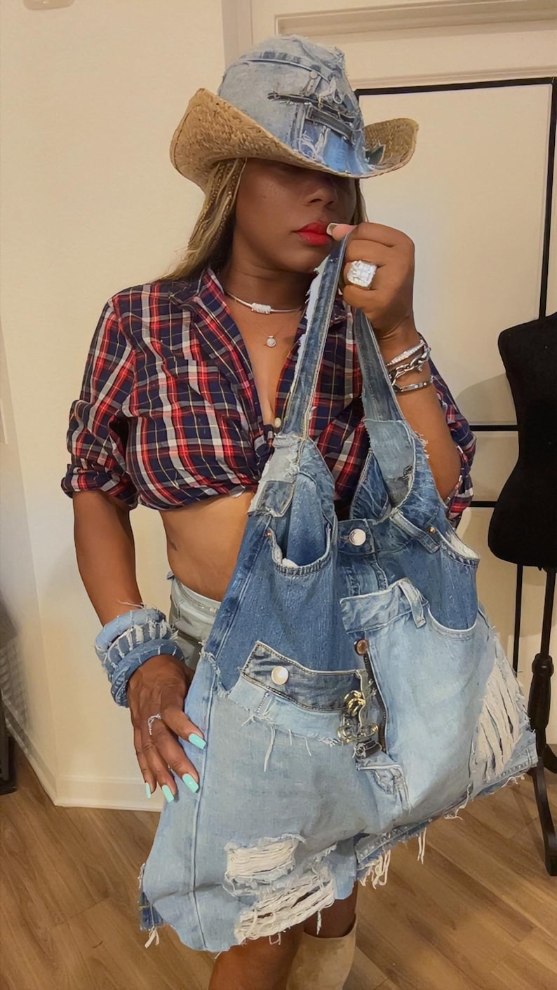 Puede incluir: Un bolso tote de mezclilla con un dise&ntilde;o de retazos, con bolsillos y detalles desgastados. El bolso se combina con un sombrero de vaquero de mezclilla a juego. El atuendo incluye una camisa a cuadros roja y azul.