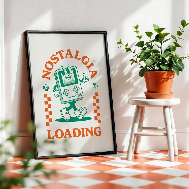 May include: Framed poster with a retro video game console illustration. The poster features the words "NOSTALGIA LOADING" in orange, with a green cartoon console giving a thumbs up. The frame is black, and the background is white.