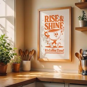 May include: A framed print with the text "Rise & Shine" and a cartoon illustration of a coffee cup with legs and arms. The text below the illustration reads "It's Coffee Time!"