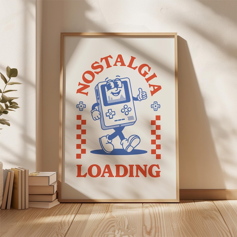 May include: A framed poster with a retro-style illustration. The artwork features a smiling, anthropomorphic handheld game console giving a thumbs-up. The word "NOSTALGIA" arches above the console, and "LOADING" is printed below. Red and blue colors dominate the design.