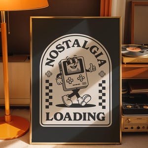 May include: Black framed poster with a retro cartoon graphic of a walking handheld game console with the words "NOSTALGIA LOADING". The design is in black and white with a gold frame.