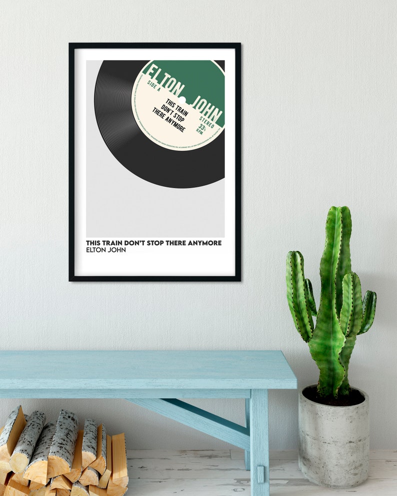 May include: A black and white framed print of a vintage record with the text "ELTON JOHN" and "THIS TRAIN DON'T STOP THERE ANYMORE" on a white background.