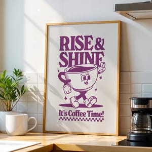 May include: A framed print with a purple cartoon coffee cup character walking and the text "Rise & Shine It's Coffee Time!"