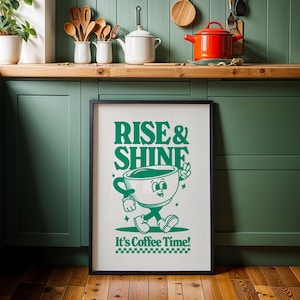 May include: A framed green and white poster with the text "Rise & Shine" and a cartoon coffee cup with a face and arms. The text "It's Coffee Time!" is below the cartoon coffee cup.