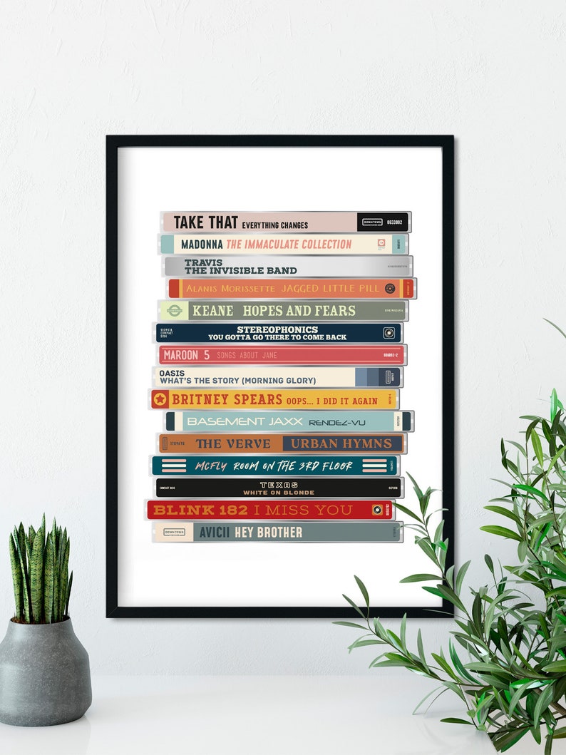 May include: A framed print of a stack of cassette tapes with the titles of popular albums from the 1990s and 2000s. The titles include "Take That", "Madonna", "Travis", "The Invisible Band", "Alanis Morissette", "Keane", "Stereophonics", "Maroon 5", "Oasis", "Britney Spears", "Basement Jaxx", "The Verve", "McFly", "Blink 182", and "Avicii".