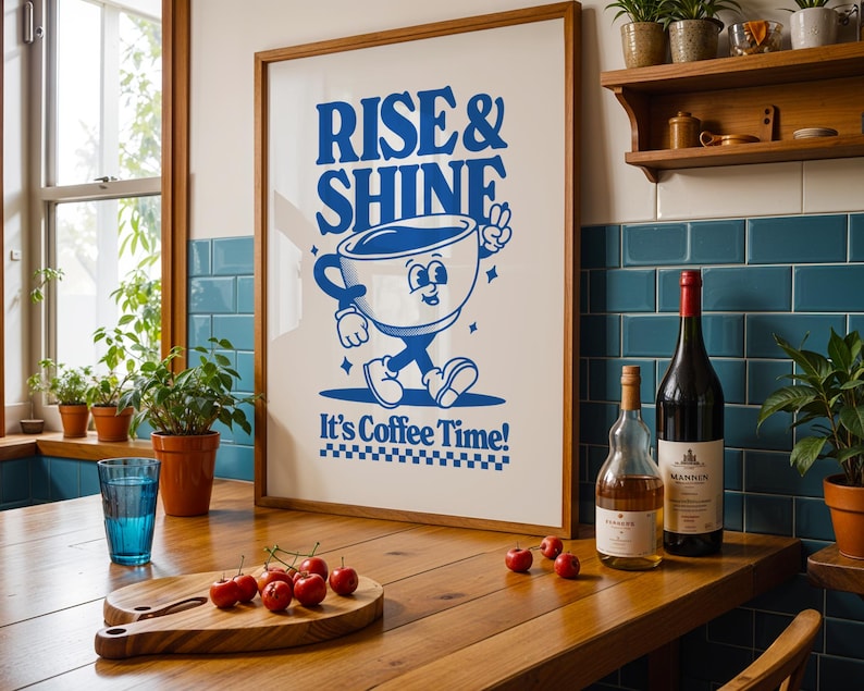 May include: A framed poster with a blue cartoon coffee cup character walking and holding a peace sign. The poster says "Rise & Shine" and "It's Coffee Time!"