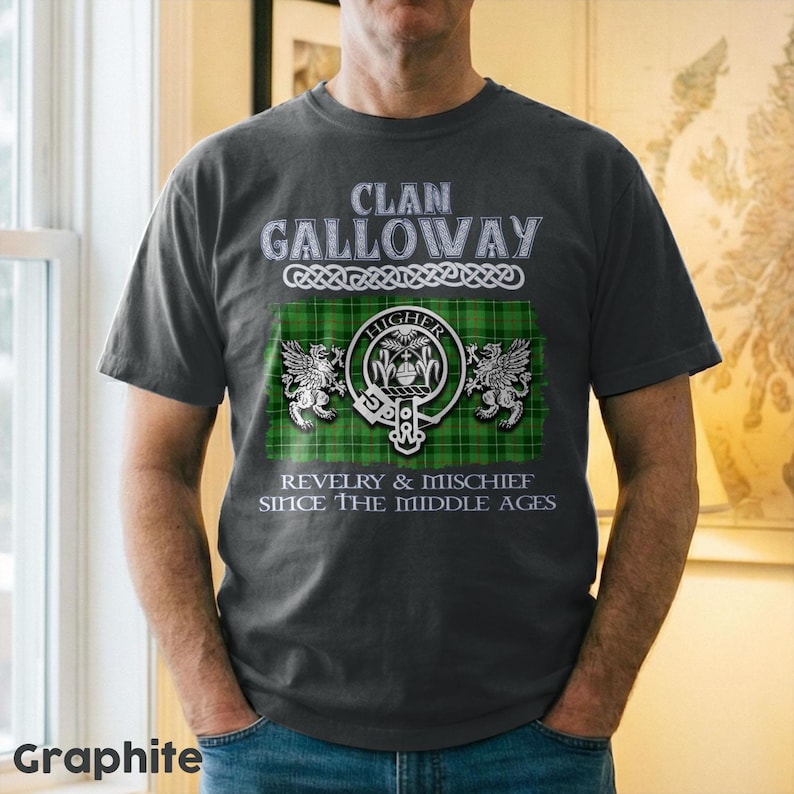 May include: Graphite gray t-shirt featuring the text "Clan Galloway" above a green and black plaid design with a crest and the words "Revelry & Mischief Since The Middle Ages."