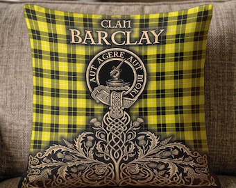 May include: A square throw pillow featuring a yellow and black tartan plaid pattern. The text CLAN BARCLAY appears above a circular crest with the motto AUT AGERE AUT MORI and a hand holding a dagger. The bottom displays ornate brown thistle motifs.