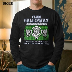 May include: Black long-sleeve shirt with the text "Clan Galloway" above a green and white plaid design. The design includes a crest with the word "Higher" and the phrase "Revelry & Mischief Since The Middle Ages."