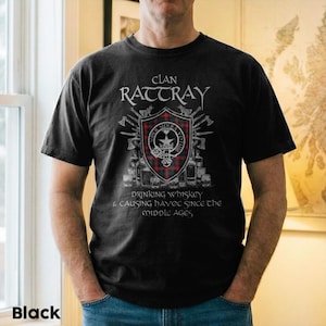 May include: Black t-shirt with the Clan Rattray crest, a shield with a red and green tartan pattern, surrounded by axes and bottles. The shirt includes the text "Clan Rattray" and "Drinking Whiskey & Causing Havoc Since the Middle Ages."