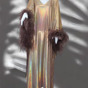 May include: A long, gold iridescent kaftan with brown feather trim on the sleeves.
