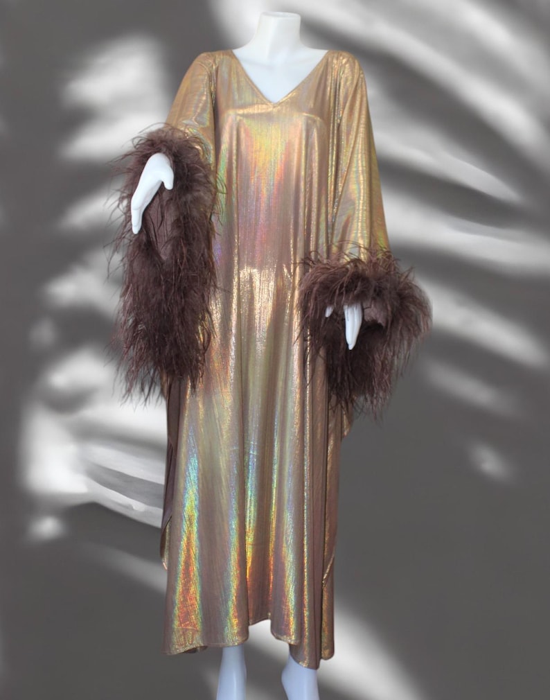 May include: A long, gold iridescent kaftan with brown feather trim on the sleeves.