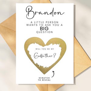 Pu&ograve; includere: Una carta a grattare a forma di cuore in lamina dorata con il testo "Vuoi essere il mio padrino?" e il nome "Brandon" in alto. La carta ha il testo "Gratta per rivelare" in basso.