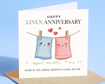 May include: A square linen anniversary card with a light blue background. The card features the words "Happy Linen Anniversary" and "Here's to Linen Happily Ever After." Two cartoon towels, one blue and one pink, hang on a clothesline with wooden clothespins.