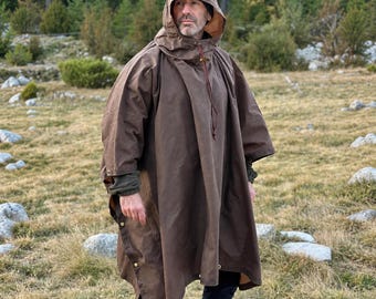 May include: A brown hooded poncho featuring a high collar with a drawstring, long sleeves, and side snap button closures. The garment is constructed from a solid-colored, durable fabric and provides full coverage over the upper body.