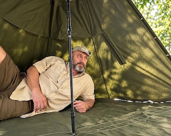 May include: An olive green canvas teepee tent featuring a central black adjustable support pole. The tent has a reinforced floor with visible white stitching and a conical structure that provides a spacious interior shelter.
