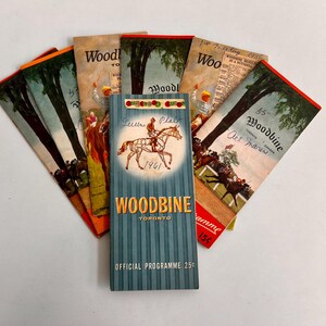 May include: A collection of vintage Woodbine horse racing programs from Toronto, Canada. The programs feature illustrations of horses and jockeys, with text including "Woodbine" and "Official Programme". The central program is teal with a horse and rider graphic.