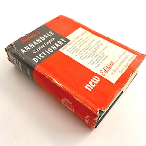 May include: A vintage dictionary titled "Blackie's Annandale Concise English Dictionary" with a bright red cover and black spine. The book has a "new edition" sticker and includes text about pronunciation and foreign words.