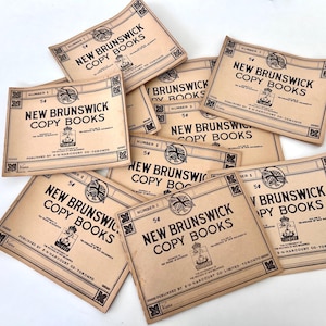 Peut inclure: Plusieurs cahiers de copie anciens de la Nouvelle-Écosse, chacun avec une couverture beige et du texte noir. Les cahiers sont numérotés et comportent le texte "New Brunswick Copy Books" et le prix "5¢".