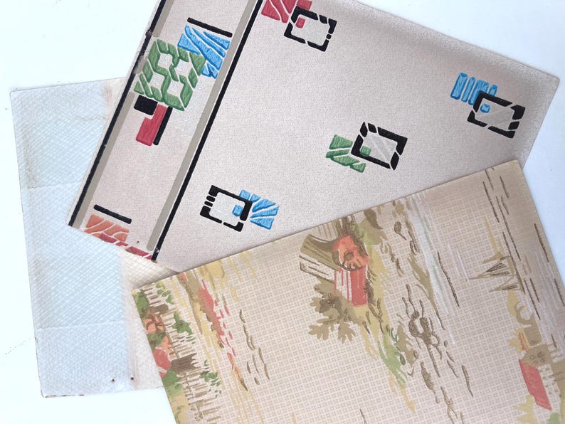 May include: A collection of vintage wallpaper samples. One sample features a geometric design with black, red, blue, and green shapes on a cream background. Another has a landscape scene with red and green accents.