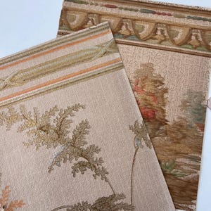May include: Two pieces of vintage wallpaper with a beige background. One piece features a floral design with brown and gold accents. The other piece has a decorative border with a landscape scene in shades of brown, green, and red.