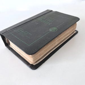 May include: Vintage black book with the title "SEA TUBE HANDBOOK" in green lettering. The book has a dark cover and aged, yellowed pages. The book is bound with metal rings and is likely a technical manual or reference guide.