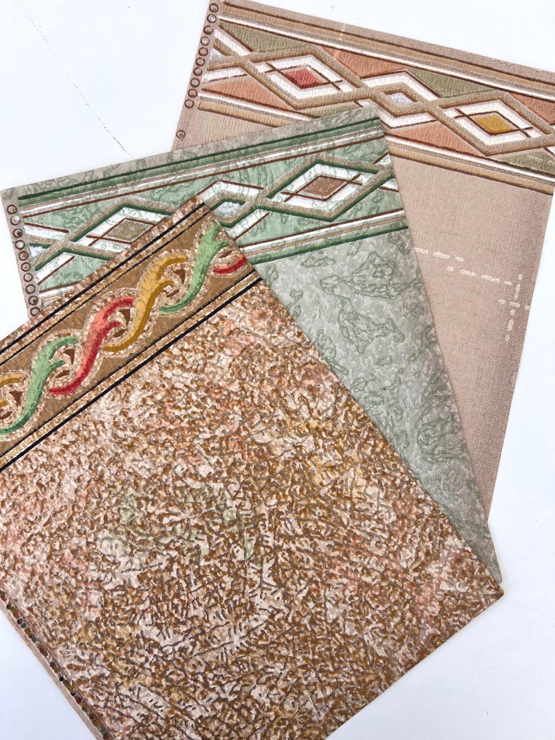 May include: A collection of vintage wallpaper samples. The samples feature various patterns, including geometric diamond shapes, wavy lines, and textured backgrounds in shades of brown, green, and beige. The edges have decorative borders.
