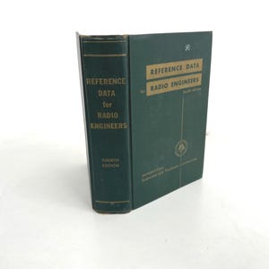 May include: A vintage green book titled "Reference Data for Radio Engineers, Fourth Edition." The book has gold lettering and a logo on the cover. The book is standing upright on a white surface.
