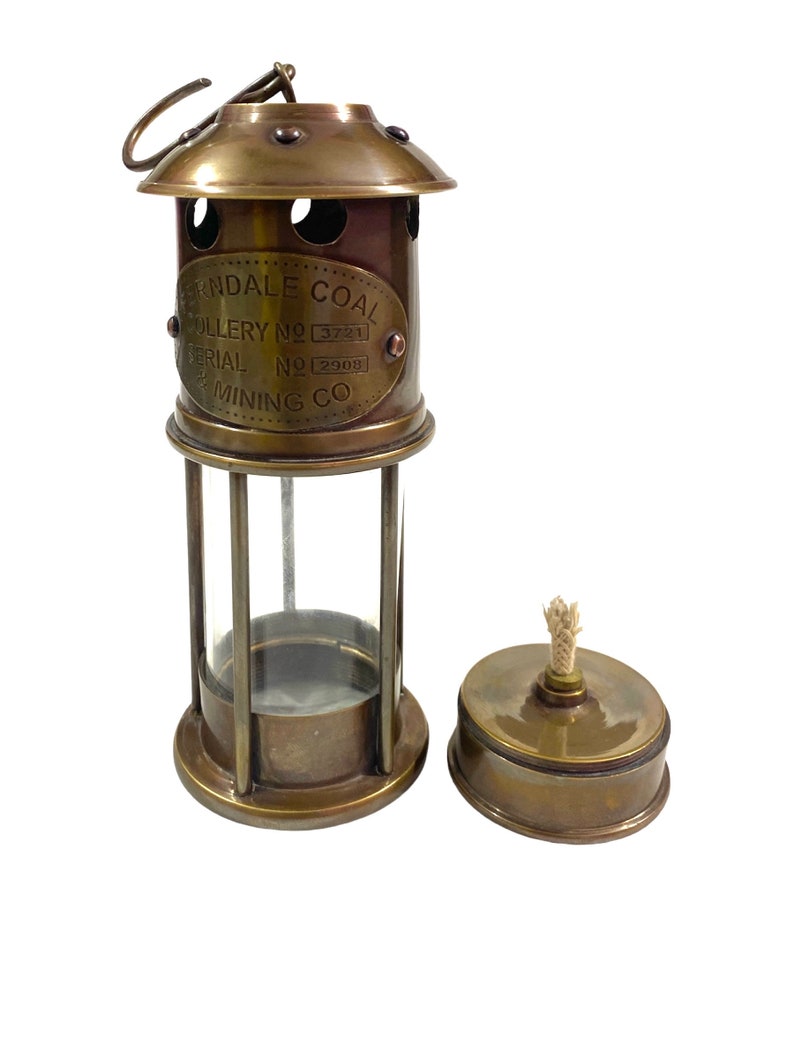 May include: Brass miner's lamp with a glass cylinder and a separate oil reservoir. The lamp has a label that reads "Ferndale Coal Colliery No. 3721 Serial No. 2908 Mining Co."