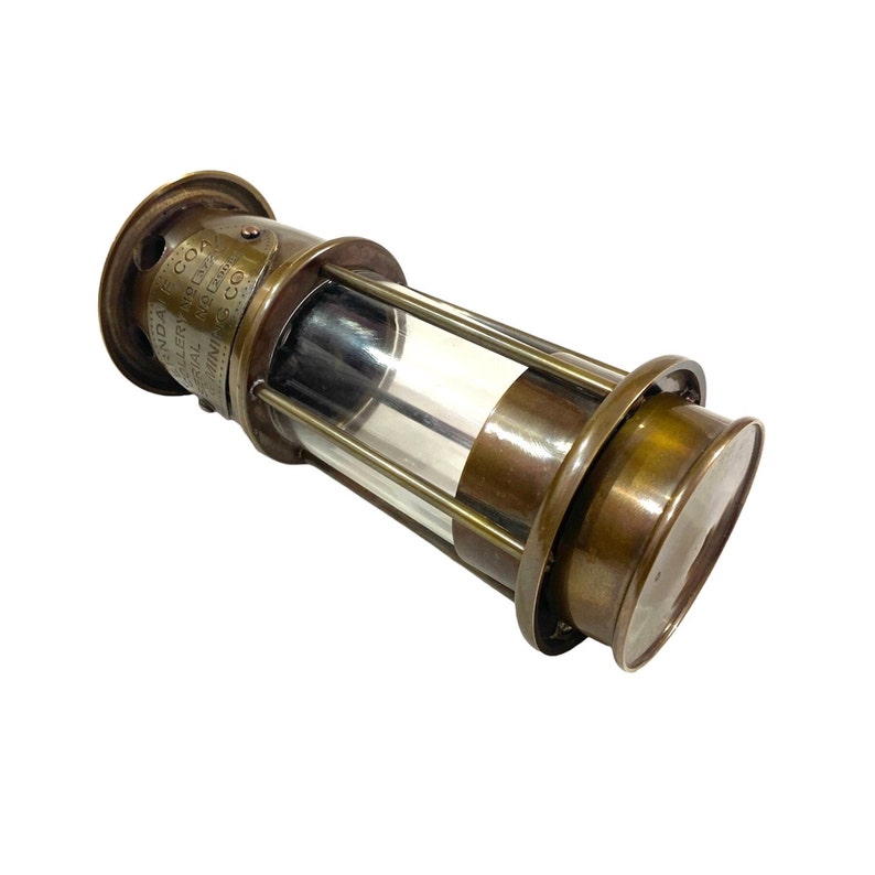 May include: A brass miner's lamp with a clear glass cylinder and a label that reads "INDIA COAL MINING CO. LTD. CALCUTTA.  APPLY FOR PERMISSION TO USE THIS LAMP.  ECO7", a vintage collectible.