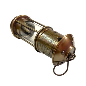 May include: Brass miner's lamp with a glass lens and a handle. The lamp is inscribed with "COAL COLLIERIES & GENERAL MINES FERNDALE CO. 2221 2008 MINNING"