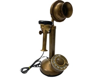 May include: A vintage brass rotary dial phone with a black receiver and a black rotary dial. The phone has a long brass arm with a black mouthpiece.