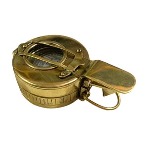K&ouml;nnte beinhalten: Ein Kompass aus Messing mit einem Klappdeckel und einem Kompasszifferblatt. Der Kompass ist in Grad und mit einer Kompassrose gekennzeichnet. Der Kompass ist so konzipiert, dass er an einer Tasche oder einem G&uuml;rtel befestigt werden kann.