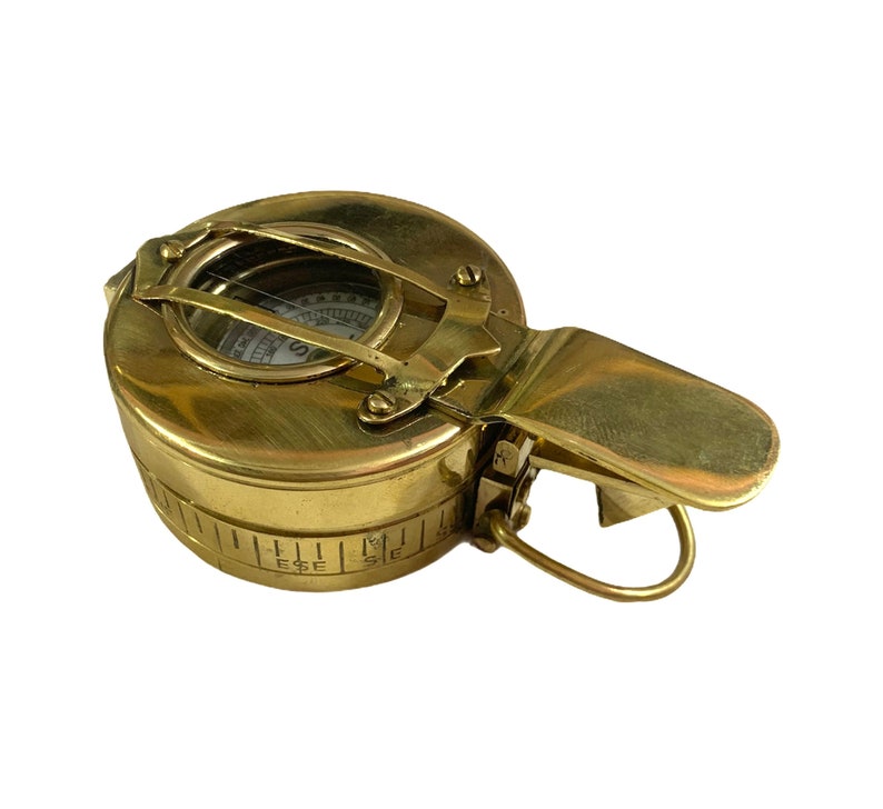 K&ouml;nnte beinhalten: Ein Kompass aus Messing mit einem Klappdeckel und einem Kompasszifferblatt. Der Kompass ist in Grad und mit einer Kompassrose gekennzeichnet. Der Kompass ist so konzipiert, dass er an einer Tasche oder einem G&uuml;rtel befestigt werden kann.