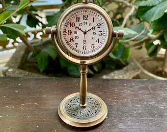 May include: A gold-toned, antique-style clock with Roman numeral markings on the face. The clock is on a decorative stand with an ornate design.