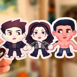 Puede incluir: Una pegatina con tres personajes de dibujos animados. Los personajes tienen cabezas grandes y cuerpos pequeños. Un personaje está sin camisa, otro lleva una camisa a cuadros y el tercero una chaqueta negra.