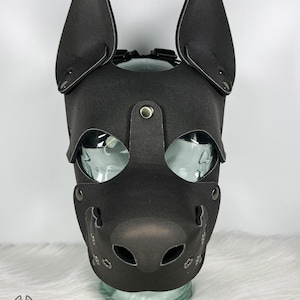 May include: Black leather pup mask with large, upright ears, eye openings, and a muzzle with air holes. The mask is secured with rivets and straps. The Grunge Bunny logo is visible at the bottom left.