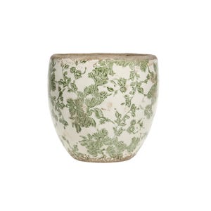 Könnte beinhalten: Ein weißer Keramiktopf mit grünem Blumenmuster. Der Topf hat eine abgerundete Form und eine leicht abgenutzte Oberfläche.