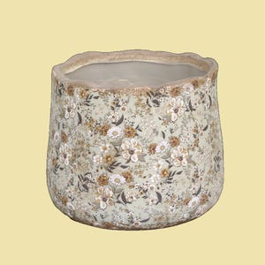 Könnte beinhalten: Ein Keramiktopf mit einem gewellten Rand und einem Blumenmuster in Braun-, Weiß- und Grüntönen.