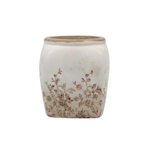 Könnte beinhalten: Weißer Keramiktopf mit leicht abgenutztem Aussehen. Der Topf hat ein braunes Blumenmuster am Boden und einen hellbraunen Rand. Das Design verleiht ihm eine Vintage- oder Antik-Ästhetik.