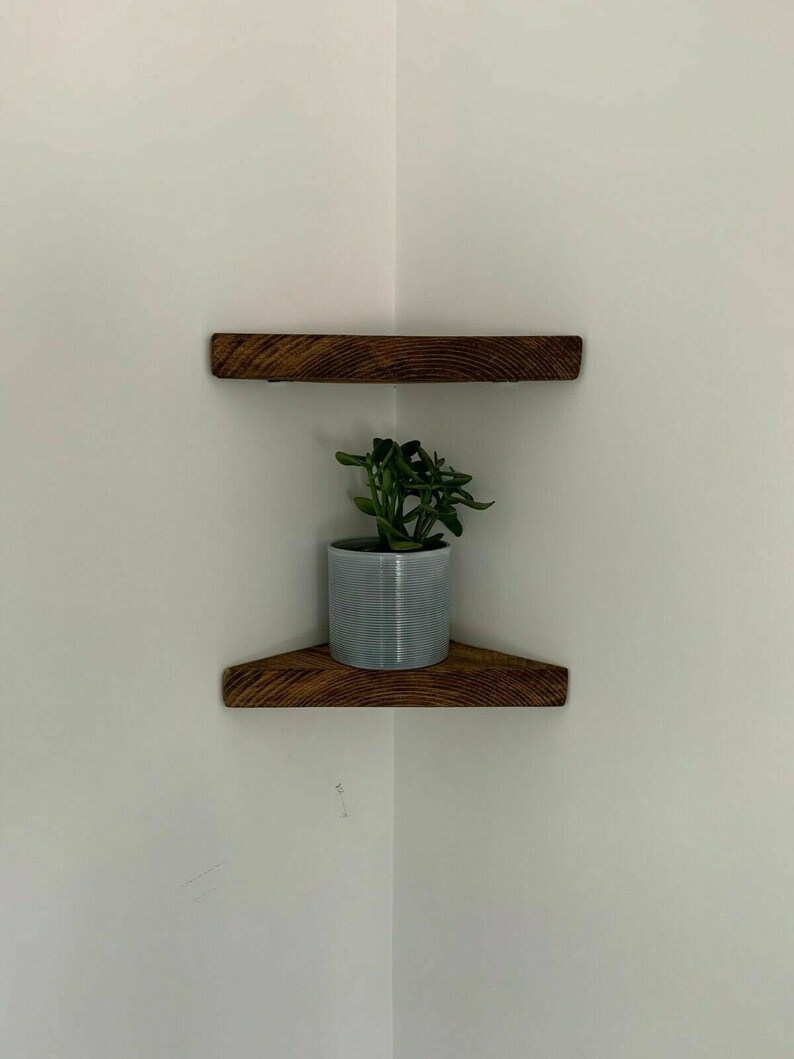 May include: Two wooden corner shelves with a small potted plant on the lower shelf.