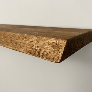 Peut inclure: Une étagère en bois rustique avec une finition brune naturelle. L'étagère a un bord légèrement irrégulier et une texture rugueuse.