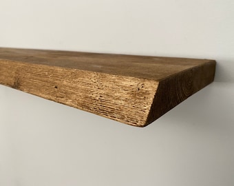 Könnte beinhalten: Ein rustikales Holzregal mit einer natürlichen braunen Oberfläche. Das Regal hat eine leicht unebene Kante und eine raue Textur.