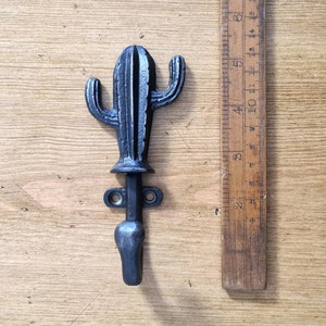 May include: Black metal cactus shaped coat hook. The hook is about 4 inches tall and has a rounded hook at the bottom.