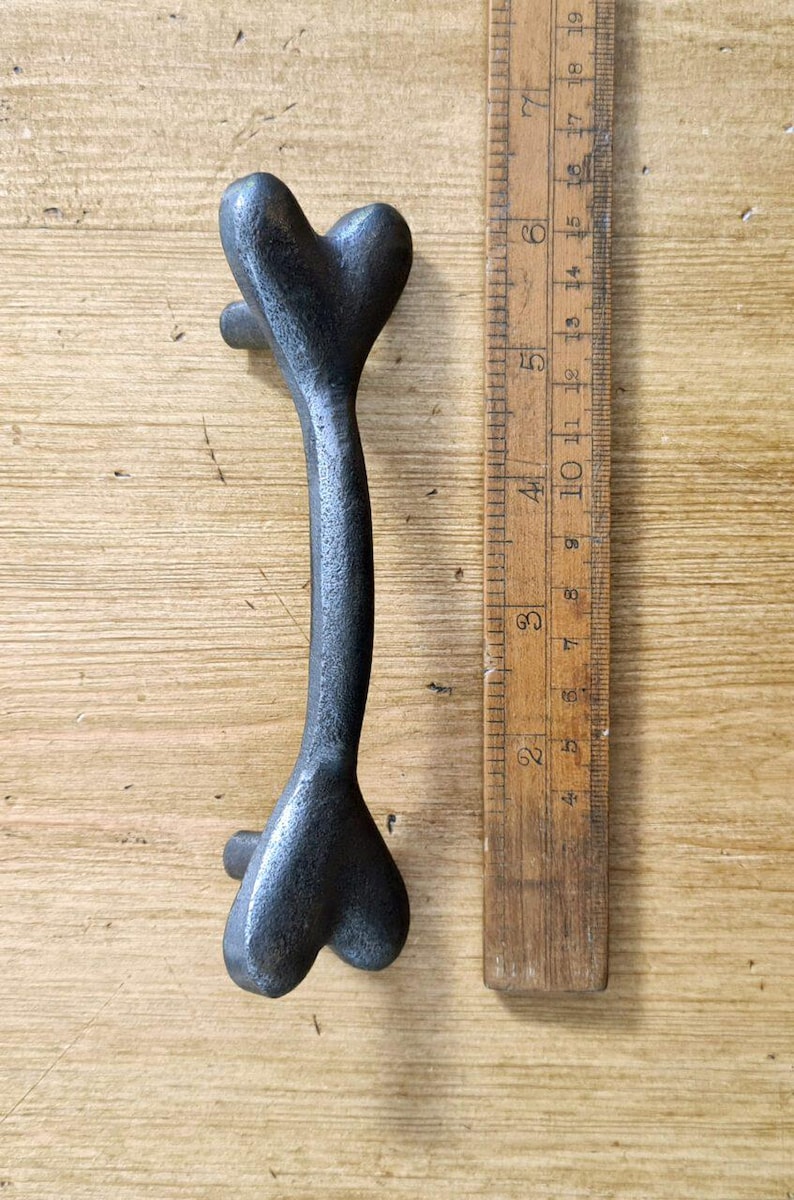 Puede incluir: Una manilla de puerta de metal negro en forma de coraz&oacute;n con un dise&ntilde;o curvo. La manilla mide aproximadamente 12,5 cm de largo.