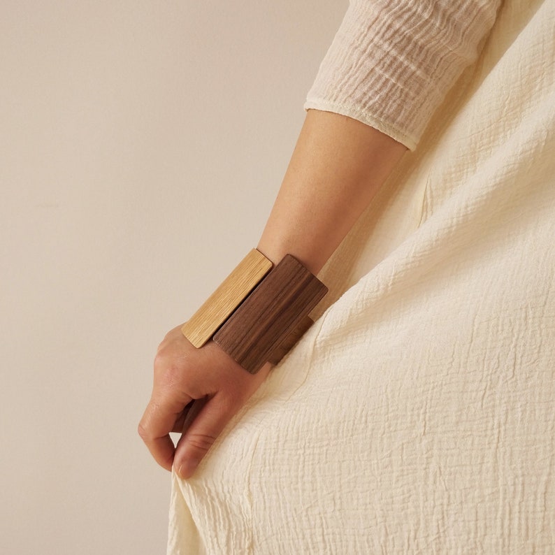 With a unique geometric shape, infused with warmth and character, this wide wooden cuff will be an eye-catching addition to your everyday wear.