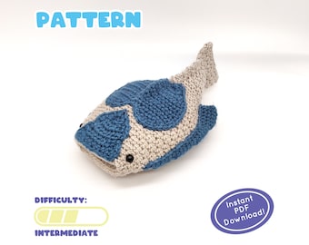 May include: A crocheted fish pattern in beige and blue. The fish has blue spots and black button eyes. The word "PATTERN" is at the top in blue, and "DIFFICULTY: INTERMEDIATE" is at the bottom. An oval sticker says "Instant PDF Download!"